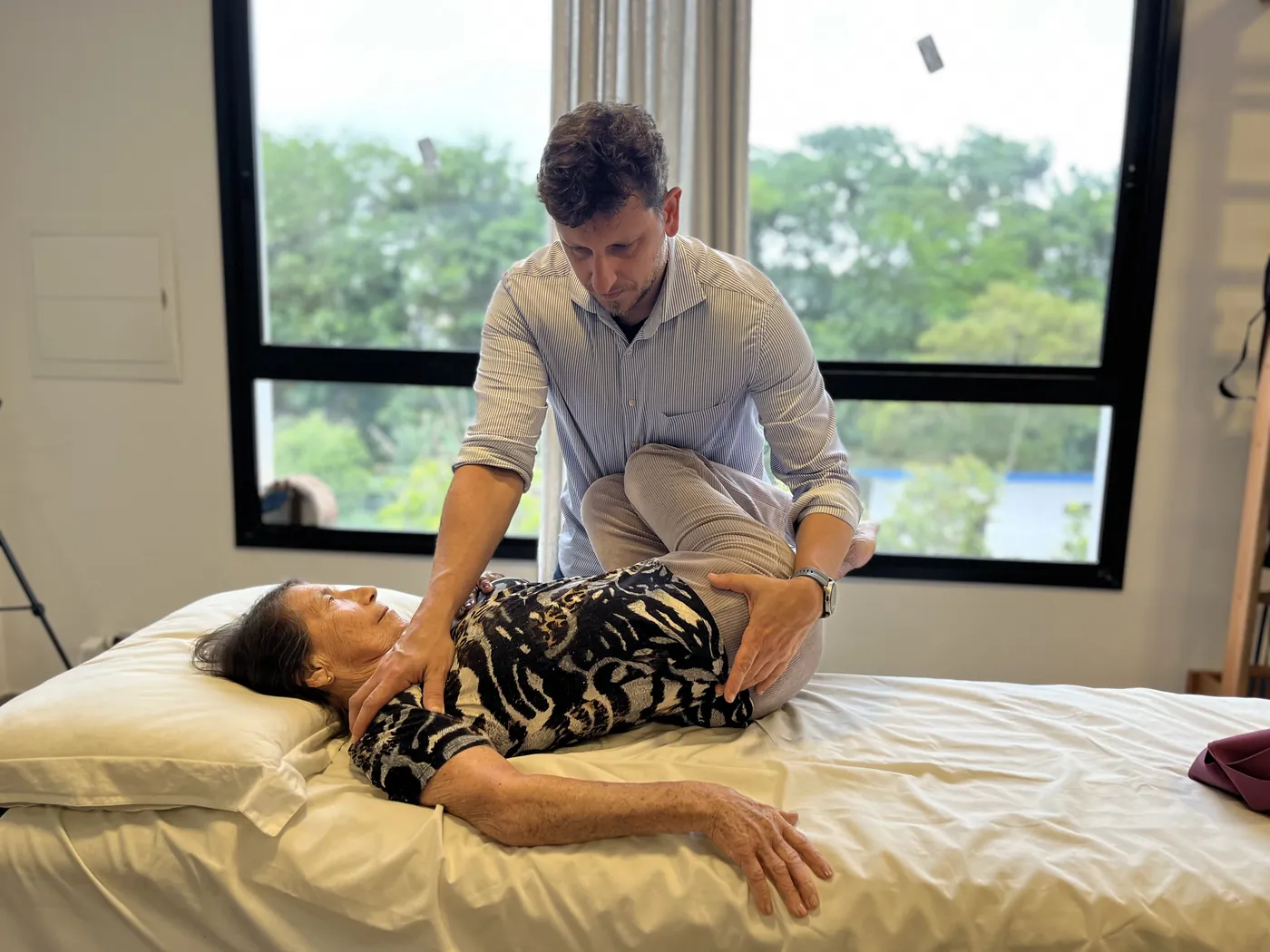 Leonardo Schneider fazendo terapia manual na coluna de uma paciente deitada na maca, no consultório em Florianópolis
